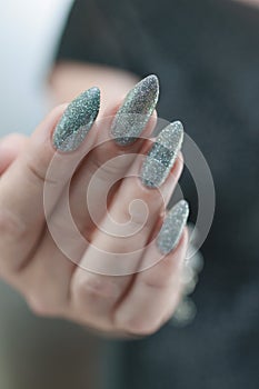 Female hand with long nails and a white gray silver manicure