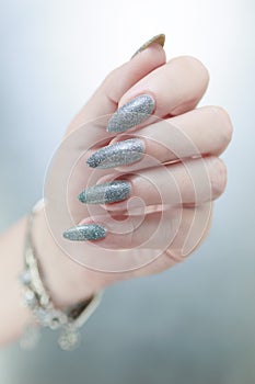 Female hand with long nails and a white gray silver manicure