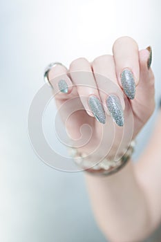 Female hand with long nails and a white gray silver manicure