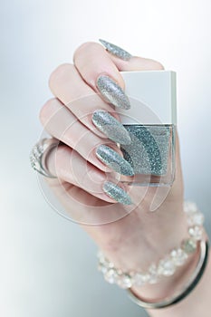 Female hand with long nails and a white gray silver manicure