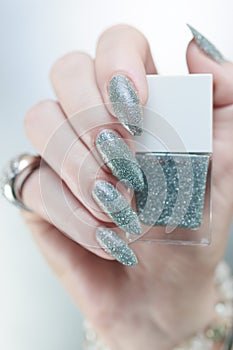 Female hand with long nails and a white gray silver manicure