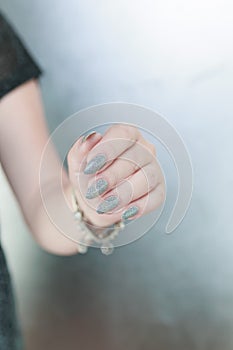 Female hand with long nails and a white gray silver manicure