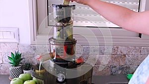 Female hand makes apple drink Juicer makes green juice from apples