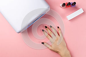 Female hand with manFemale hand with manicured nails and UV lamp photo