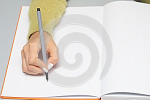 Female hand with a marker who writes on an empty notebook page