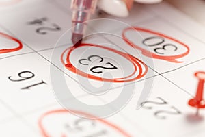 Female hand marking with a red pen on a calendar circles the day, deadline concept