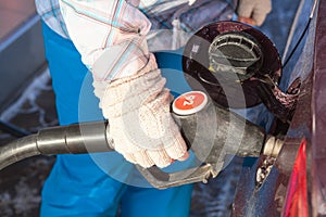 Female hand in mittens refueling vehicle