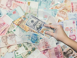 Female hand with money of south-east Asia and American hundred dollar bill. Currency of Hong Kong, Indonesia, Malaysia, Thai, Sing