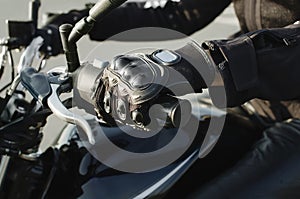 Female hand in motorcycle protective gloves holds a motorcycle, close-up