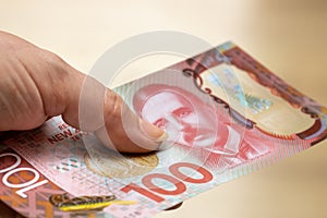 Female hand with a New Zealand 100 dollars banknote