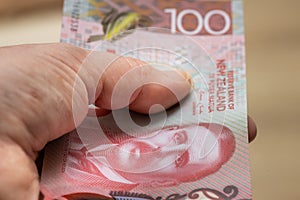 Female hand with a New Zealand 100 dollars banknote