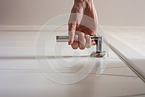 Female hand open the door. Bottom view of woman arm holds door handle. Close up of hand opening a door