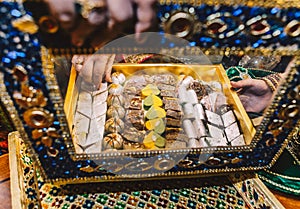 Female hand open luxury beautiful box inlaid with jewels with tasty indian candy sweets