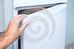 Female hand opening a fridge door, check up reserves and food freshness