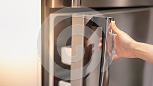 Female hand opening a refrigerator door for find the food and ingredient preparing to cooking in their home