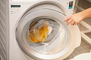 Female hand opening the washing machine prepare wash the .clothes, for the hygience and cleaning.