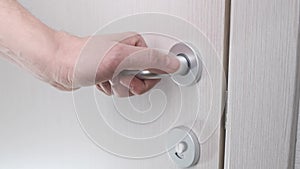 Female hand opens the door in the white bathroom. Close up.