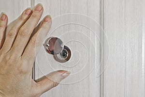 A female hand opens the shutter on the door peephole in the front door. The concept of security