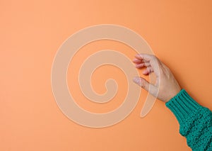 Female hand on an orange background, part of the body is holding the subject