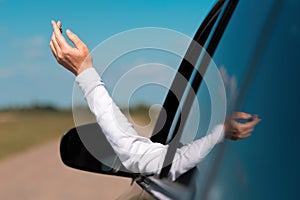 Female hand out of the car window during the ride