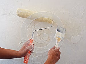 Female Hand painting the wall with paint roller and  brush. Home renovating with color