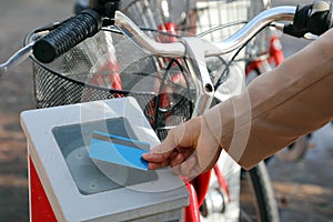 Female hand paying for bike with credit card, using modern contactless system at rental station outdoor