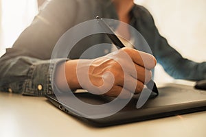 Female hand with pen-like stylus and graphic tablet