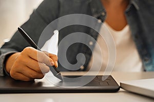 Female hand with pen-like stylus and graphic tablet