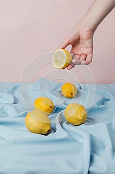 Female hand picking half of lemon from a table covered with blue drapery,