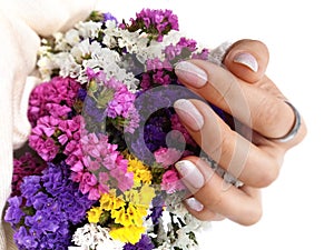 Female hand with pink manicure. Bouquet of bright flowers