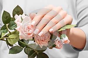 Female hand with pink nail design. Female hand hold pink rose flowers. Pink nail polish manicure with flower nail art