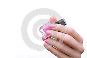 Female hand with pink nail design holding purple nail polish bottle