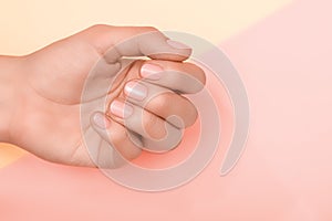 Female hand with pink nail design. Pink nail polish manicure. Female hands on pale orance pink background photo