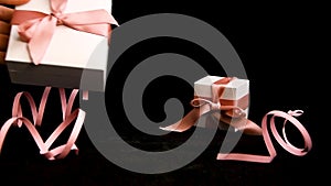 Female hand placing Present box with pink ribbon on black background