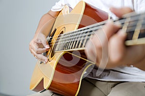 Female hand playing music by acoustic guitar