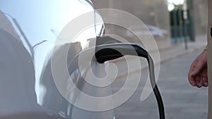 Female hand plugging out a charger from electric car. Woman gets out power cord from his auto after charges batteries