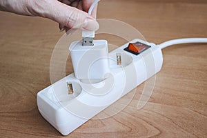 Female hand plugging usb cable into phone charger adapter