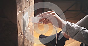 Female hand plugs the phone charger into the socket