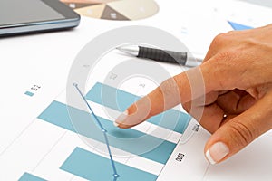 Female hand pointing at statistics.