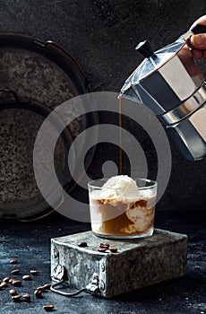 Female hand pouring coffee on vanilla ice cream to make an affogato coffee. Summer coffee drink with ice cream and espresso