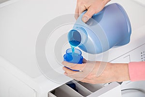 Female Hand Pouring Detergent In The Blue Bottle Cap