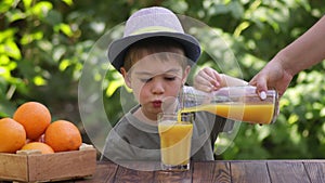 female hand pouring fresh orange juice for child