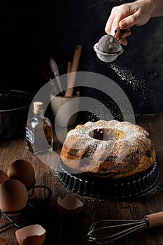 Female hand powdering marble bundt cake