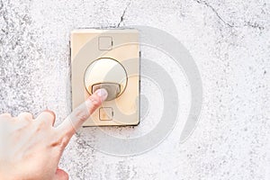Female hand press on buzzer on grunge wall n front of house