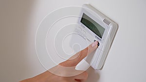 Female hand presses air conditioner button on wall closeup