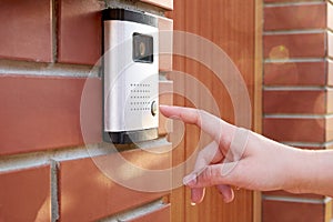 The female hand presses a button doorbell with intercom