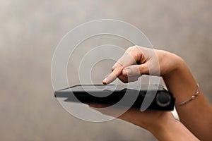 A female hand presses on the screen of a digital tablet close-up, side view. New technology concept, multimedia