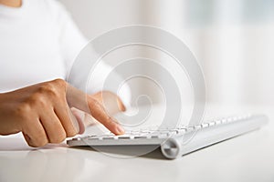 Female hand pressing enter key on wireless keyboard