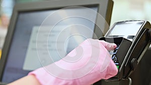 Female hand in protective gloves paying purchases with a contactless credit card