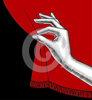 Female hand pulling aside the red curtain on black background